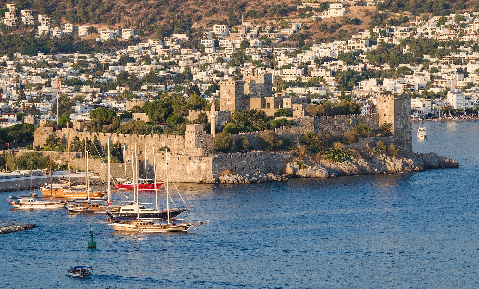 Bodrum Castle on its peninsula, with sailing boats in the bay and the town behind