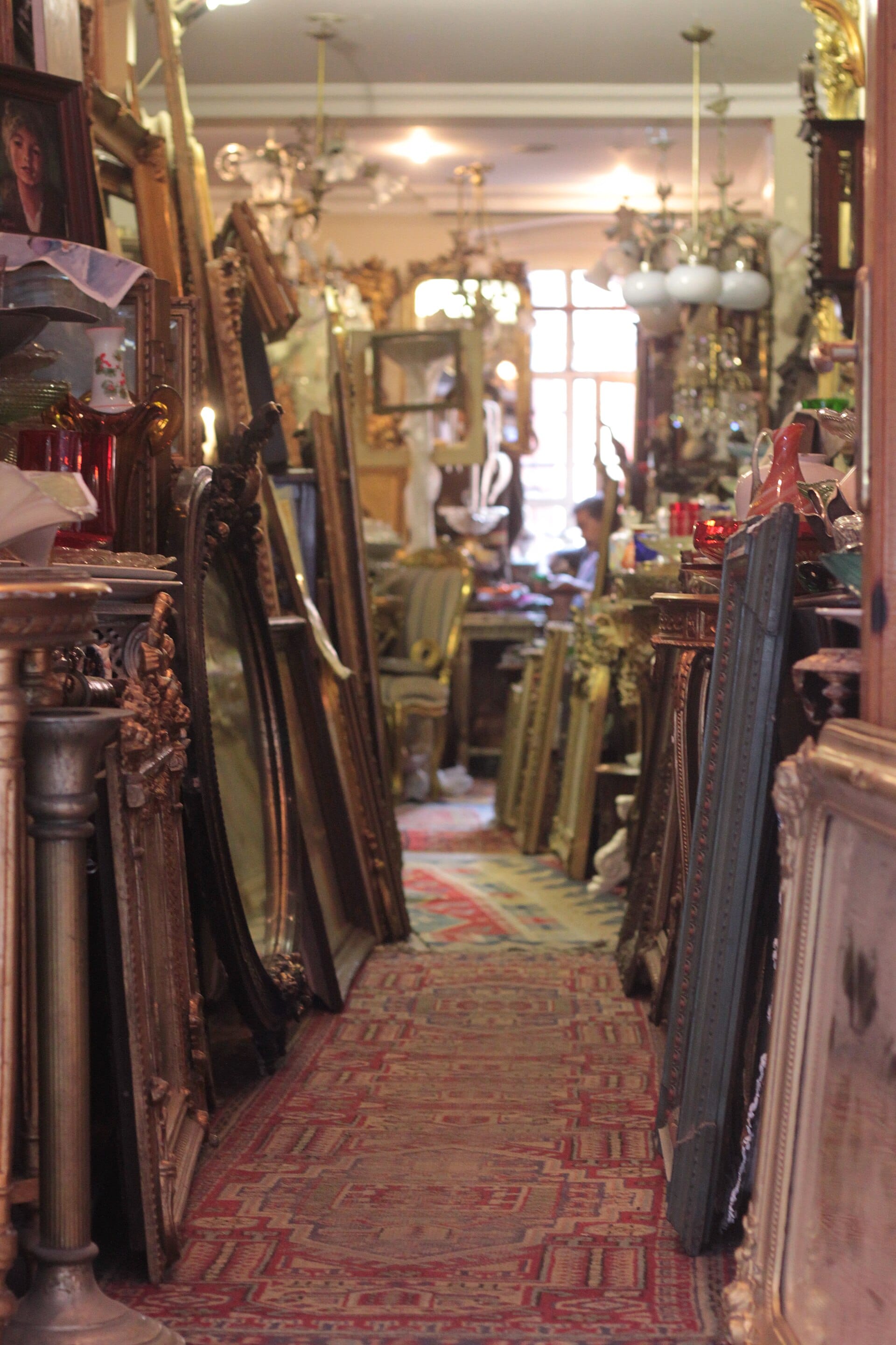 The crowded interior of an antique shop in Cihangir, filled with chandeliers and frames