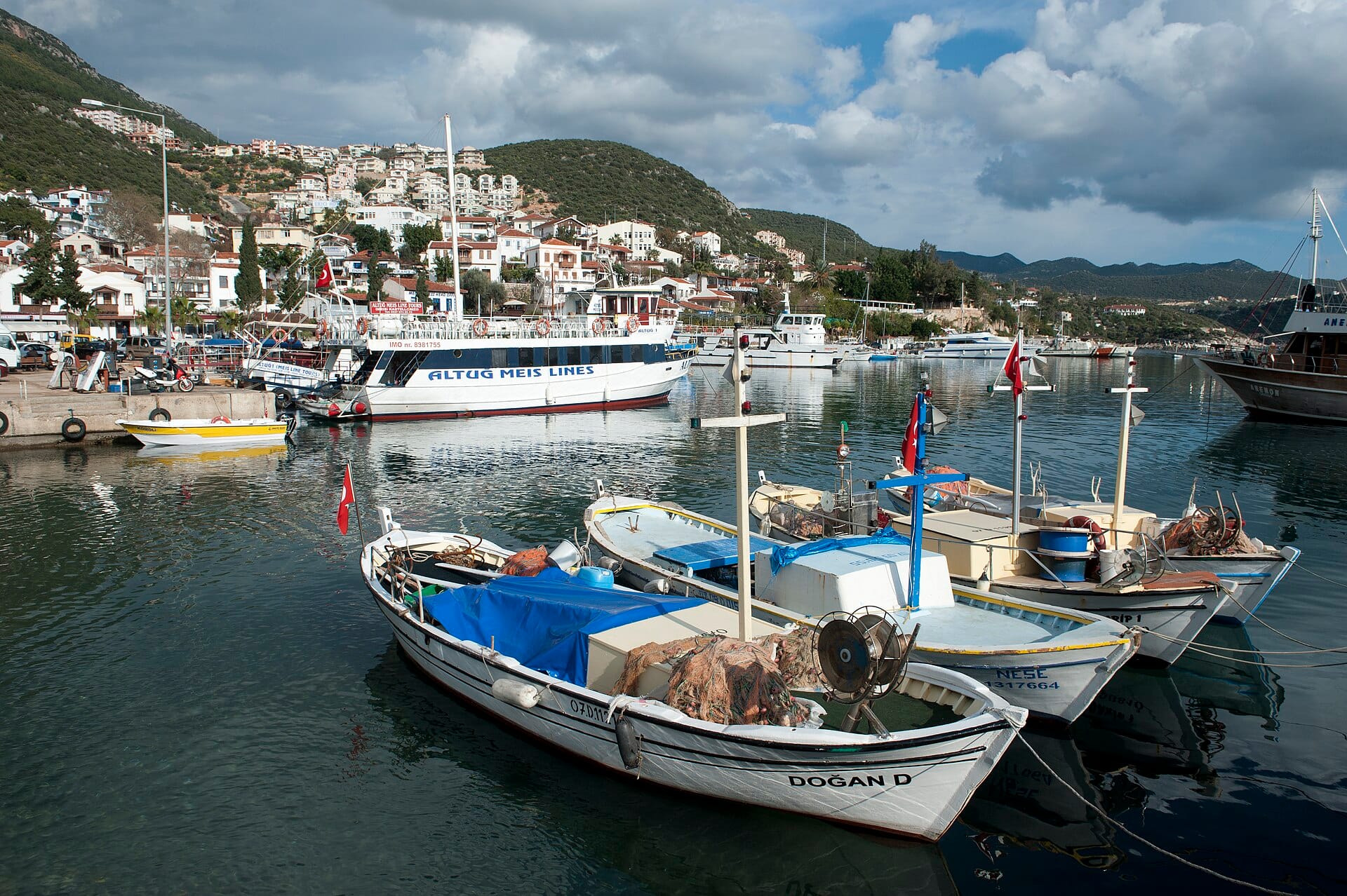 Fishing boats moored in Kaş harbour with whitewashed houses climbing the hill behind